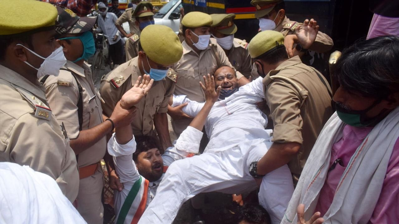  Police person attempt to detain a Congress activist during their 'symbolic' protest against frequent hikes in the prices of petrol and diesel, in front of a fuel station in Prayagraj. Credit: PTI Photo
