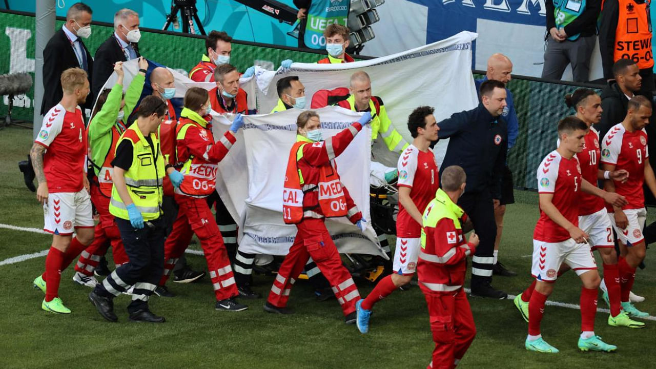 Players escort paramedics as Denmark's midfielder Christian Eriksen is evacuated from the pitch during the UEFA EURO 2020 Group B football match between Denmark and Finland at the Parken Stadium in Copenhagen on June 12, 2021. Credit: AFP Photo