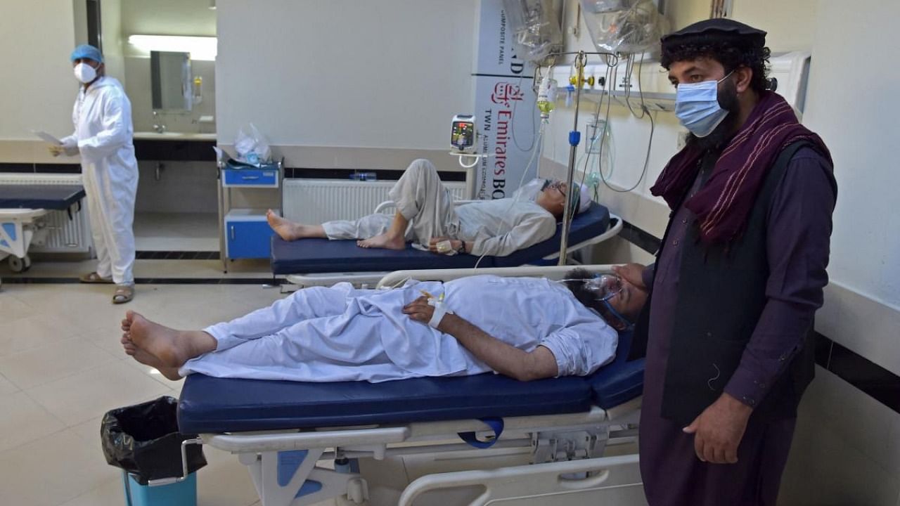 A family member stands next to a coronavirus patient at the intensive care unit (ICU) of the Muhammed Ali Jinnah hospital in Kabul. Credit: AFP Photo