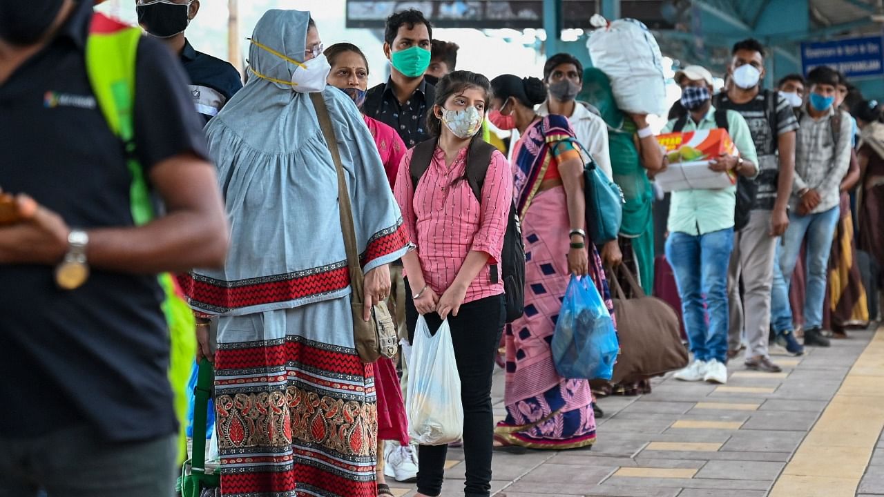 Passengers stand on a queue to get their body temperature checked during a Covid-19 coronavirus screening after arriving at a railway platform on a long distance train, in Mumbai on June 8, 2021. Credit: AFP Photo