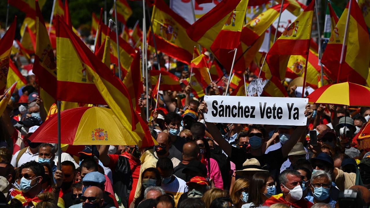 A man holds a placard reading "Sanchez leave now" as others wave Spanish flags during a protest by right-wing protesters to denounce controversial Spanish government plans to offer pardons to the jailed Catalan separatists behind the failed 2017 independence bid, in Madrid on June 13, 2021. Credit: AFP Photo