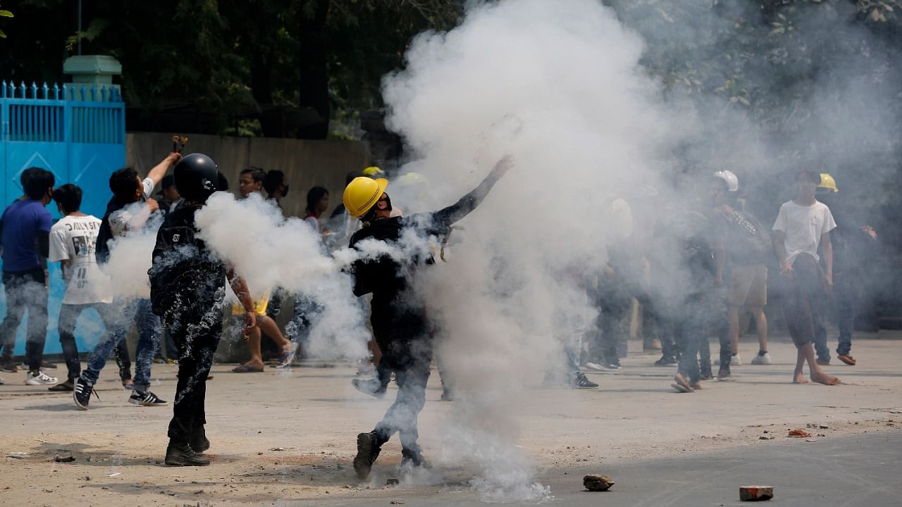 Demostrators hurl back tear gas canisters towards police during a protest against the military coup. Credit: AP Photo