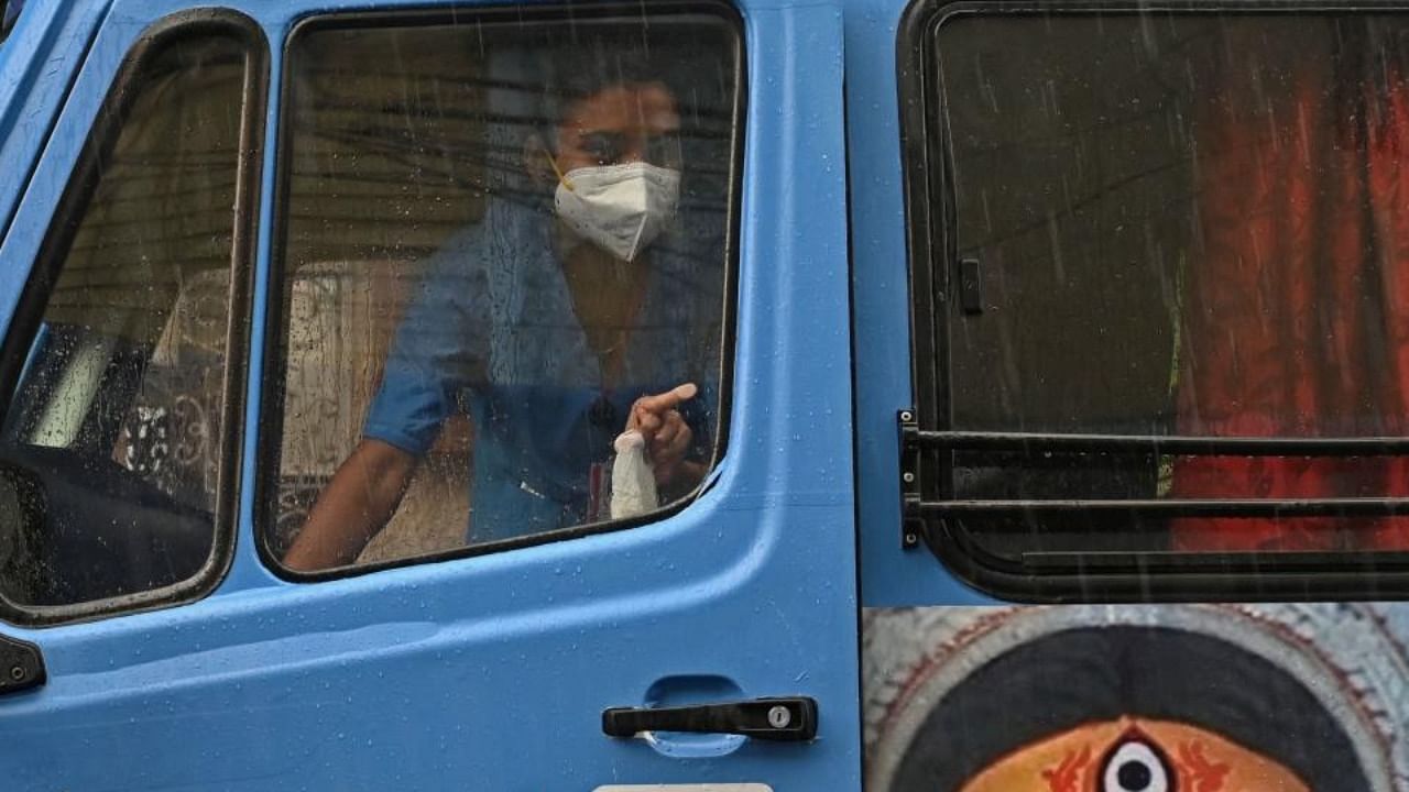 A health worker peeps out of a newly introduced 'Vaccination on Wheel', a mobile vehicle for vaccination, before she inoculates people with the Covid-19 vaccine in Kolkata on June 14, 2021. Credit: AFP Photo