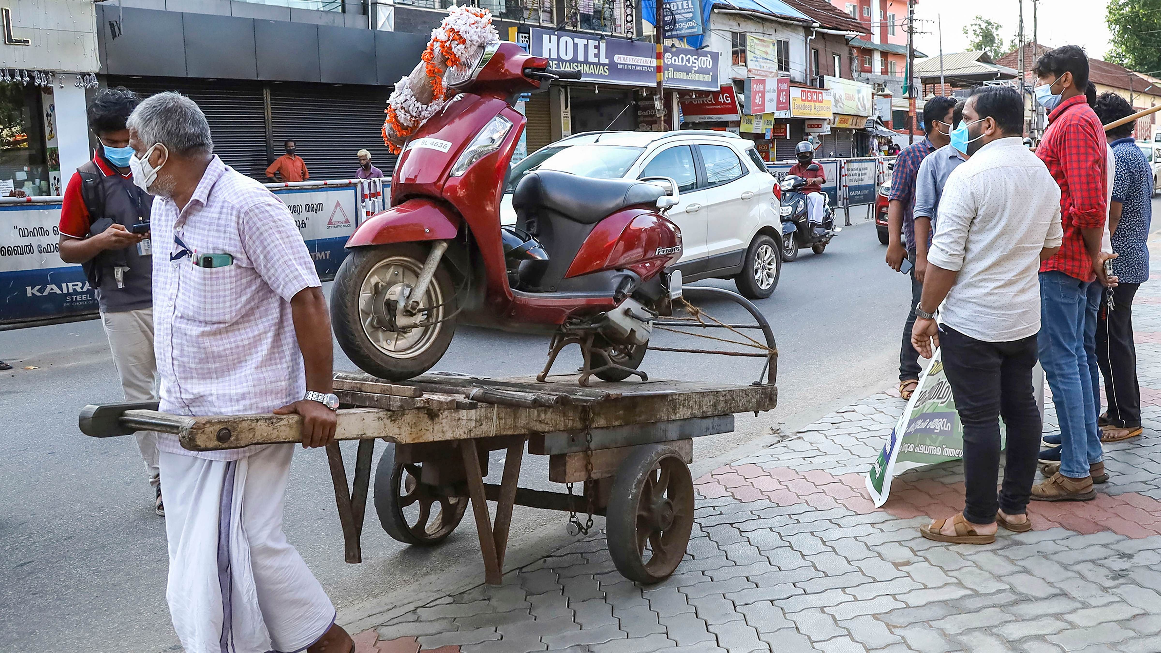 An IUML activist pulls a trolley with a scooter on top to protest against petrol and diesel price hike, in Kozhikode. Credit: PTI File Photo/ Representative