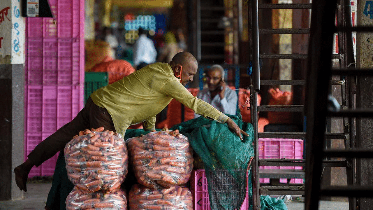 A vendor covers sacks of vegetables at a wholesale market in Navi Mumbai. Credit: AFP Photo