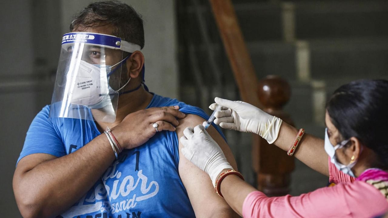 A health worker administers a dose of Covid-19 vaccine to a man, at a vaccination centre in Gurugram. Credit: PTI Photo