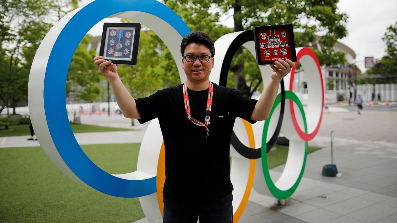 Yoshiyuki Terajima, a pin collector based in Tokyo, shows his collection next to the Olympic rings monument in Tokyo. Credit: Reuters Photo