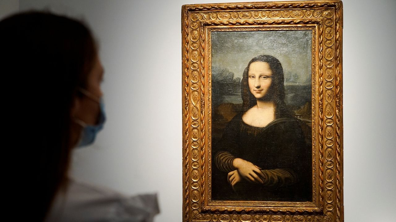 A woman looks at the Hekking "Mona Lisa", a reproduction of Leonardo Da Vinci's Mona Lisa, painted on canvas by an unknown artist from the 17th century and up for an online sale at Christie’s auction house in Paris, France, June 11, 2021. Credit: Reuters Photo
