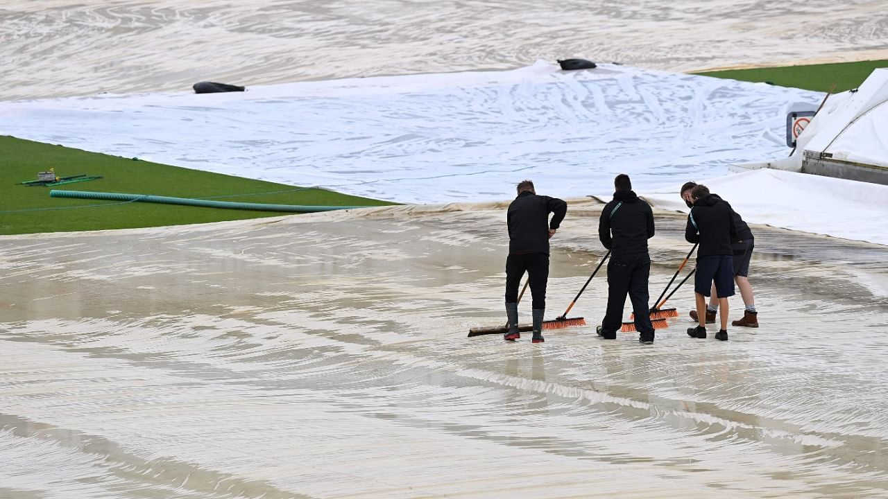 Ground staff sweep water from the covers on the first day of the ICC World Test Championship Final between New Zealand and India at the Ageas Bowl in Southampton. Credit: AFP Photo