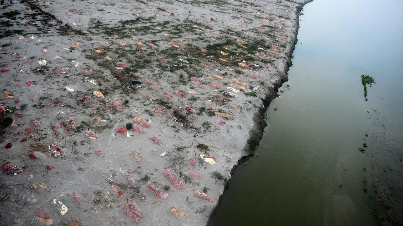 Shallow graves in the sand, some of which are suspected to be of people who died due to the Covid-19 coronavirus, are seen near a cremation ground on the banks of Ganges River, at Phafamau ghat in Allahabad. Credit: AFP Photo