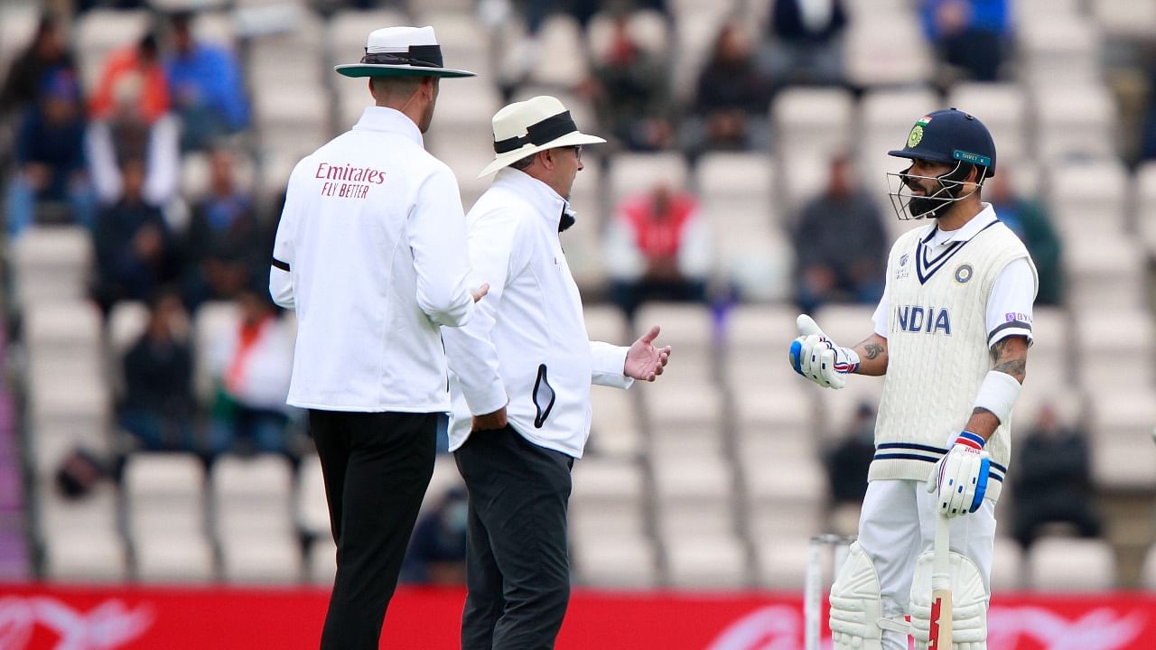 India captain Virat Kohli (R) interacts with the umpires during the Day 2 of the World Test Championship final as bad light stops play. Credit: AP/PTI Photo