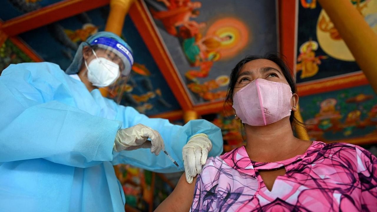 A woman receives China's Sinopharm Covid-19 coronavirus vaccine at a pagoda in Kandal province. Credit: AFP Photo