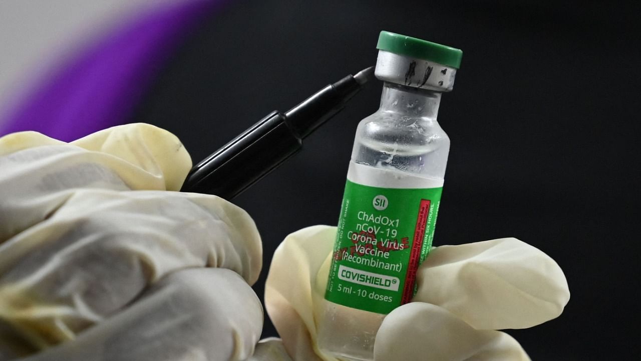 A health worker marks a vial of Covishield. Credit: AFP Photo