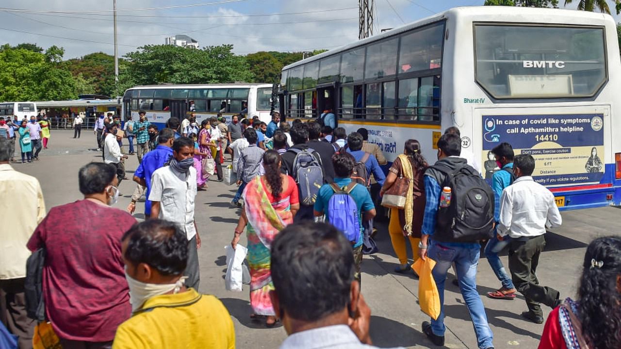 People rush to board a bus after further ease in lockdown restrictions in Bengaluru on Monday. Credit: PTI Photo
