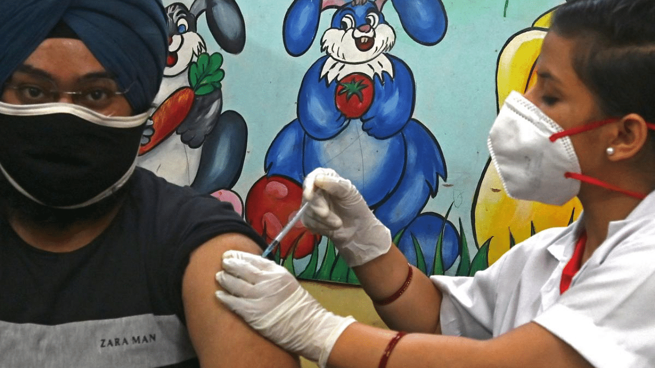 A health worker inoculates a man with a jab of coronavirus vaccine at a vaccination Centre in New Delhi. Credit: AFP Photo