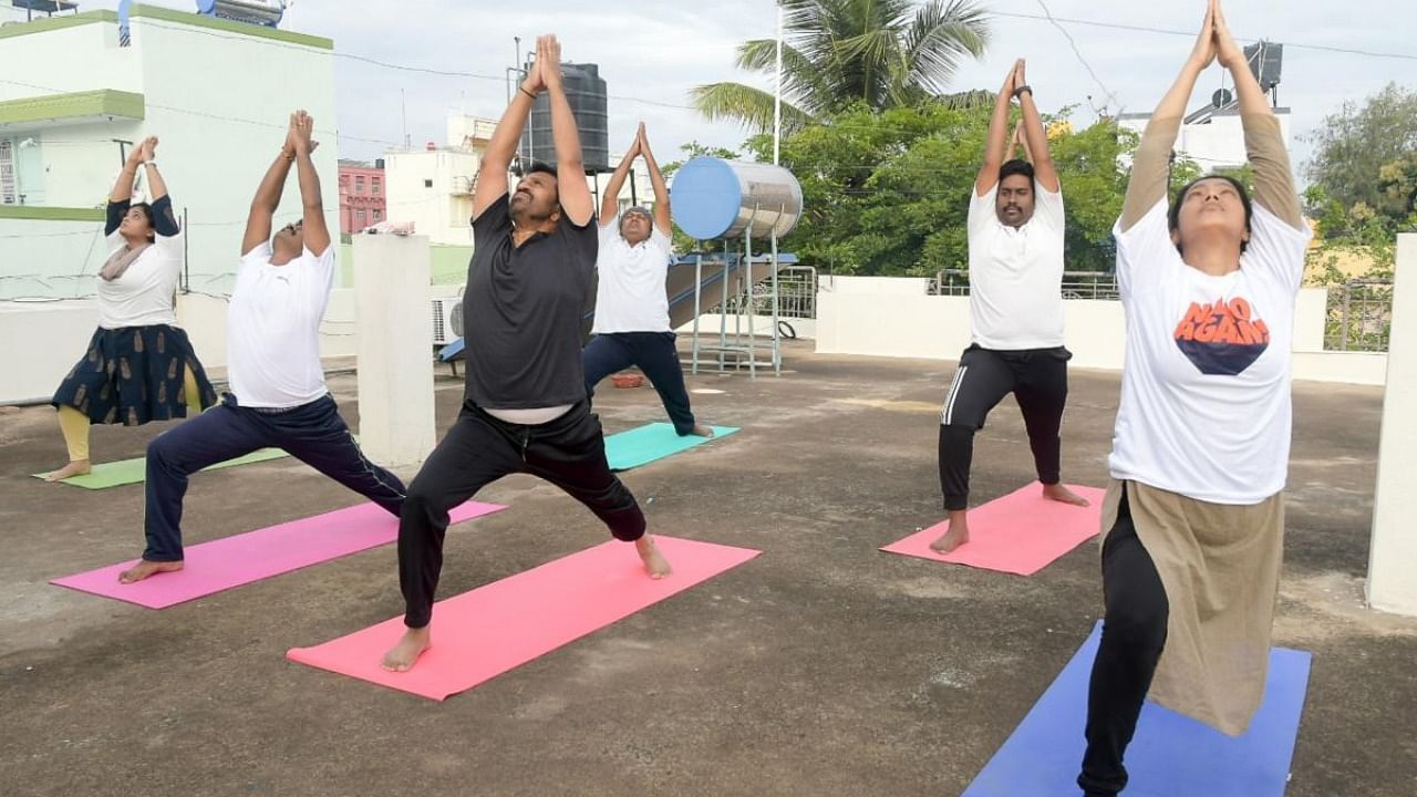 MLA L Nagendra performs Yoga as part of International Day of Yoga in Mysuru on Monday. Corporator C Vedavathi is seen. Credit: DH Photo