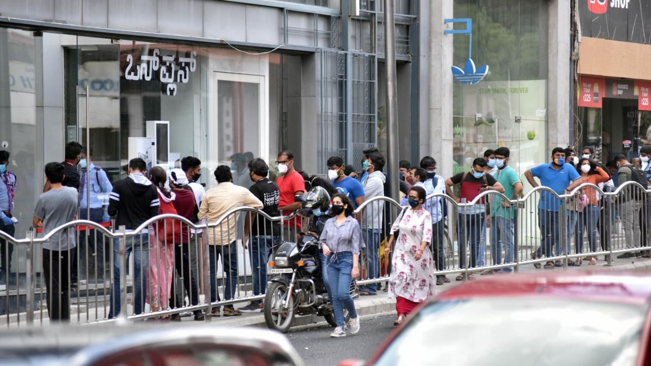 Customers stand in front of a mobile shop on Brigade road in Bengaluru on Monday. Credit: DH Photo