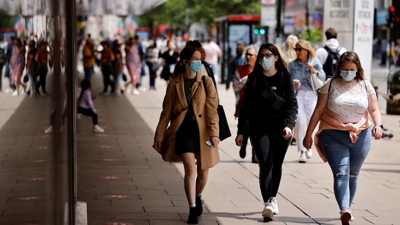Pedestrians wearing a face mask or covering due to the Covid-19 pandemic, walk along Oxford Street in central London. Credit: AFP Photo