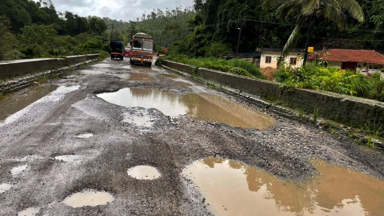 Road users find it difficult to move on Bengaluru-Mangaluru national highway near Yettinahalla village in Sakleshpur taluk due to potholes filled with rainwater. Credit: DH Photo/Janakere Paramesh