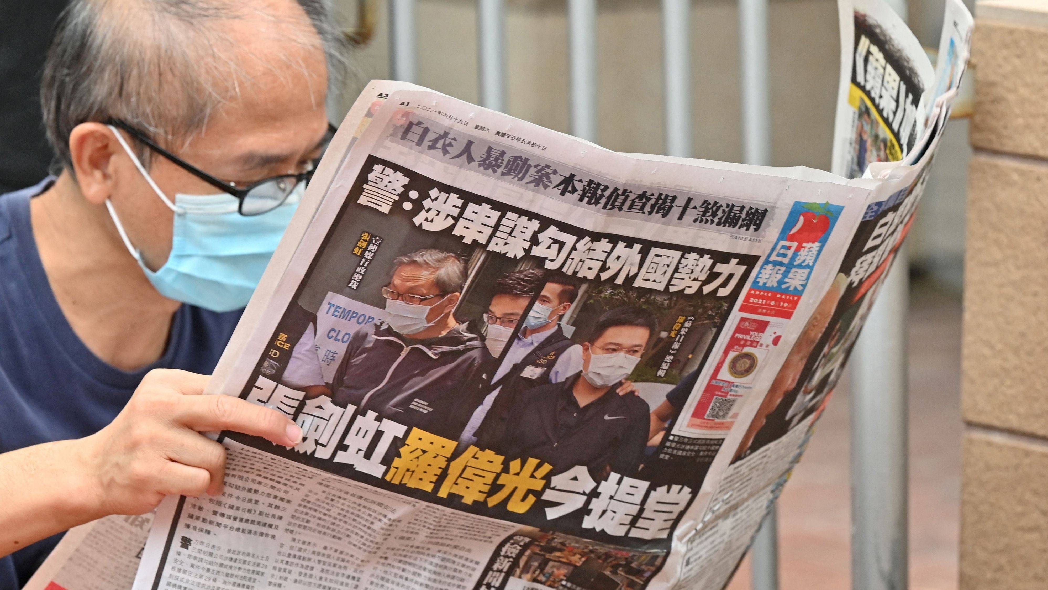 This file photo taken on June 19, 2021 shows a supporter reading a copy of the Apple Daily newspaper outside a court in Hong Kong. Credit: AFP Photo