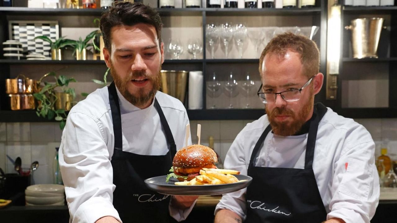 Israeli Chef Shachar Yogev (L) and his assistant Itamar Whiteson prepare burger made with "cultured chicken" meat at a restaurant adjacent to the SuperMeat production site in the central Israeli town of Ness Ziona. Credit: AFP Photo