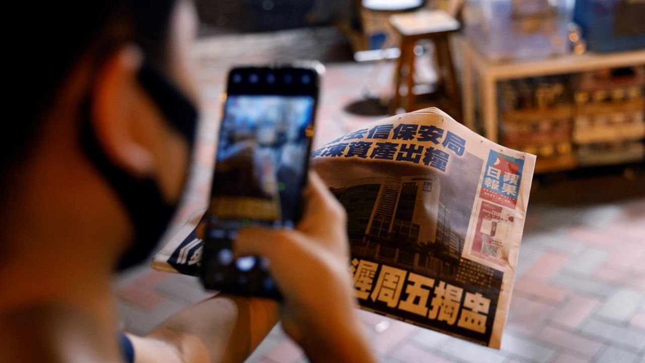 A man takes a photo of his copy of the Apple Daily newspaper after it looked set to close for good by Saturday following police raids and the arrest of executives in Hong Kong. Credit: Reuters Photo
