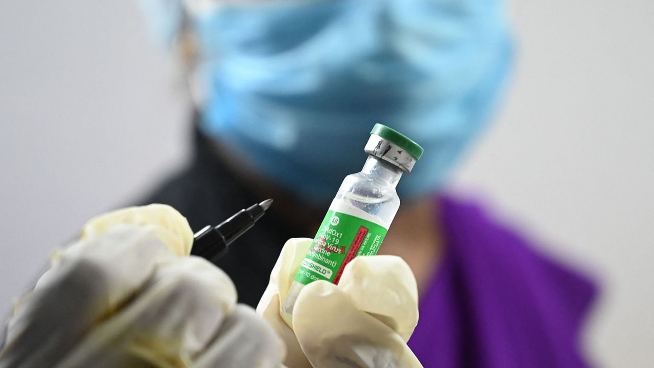 A health worker marks a vial of Covishield. Credit: AFP Photo