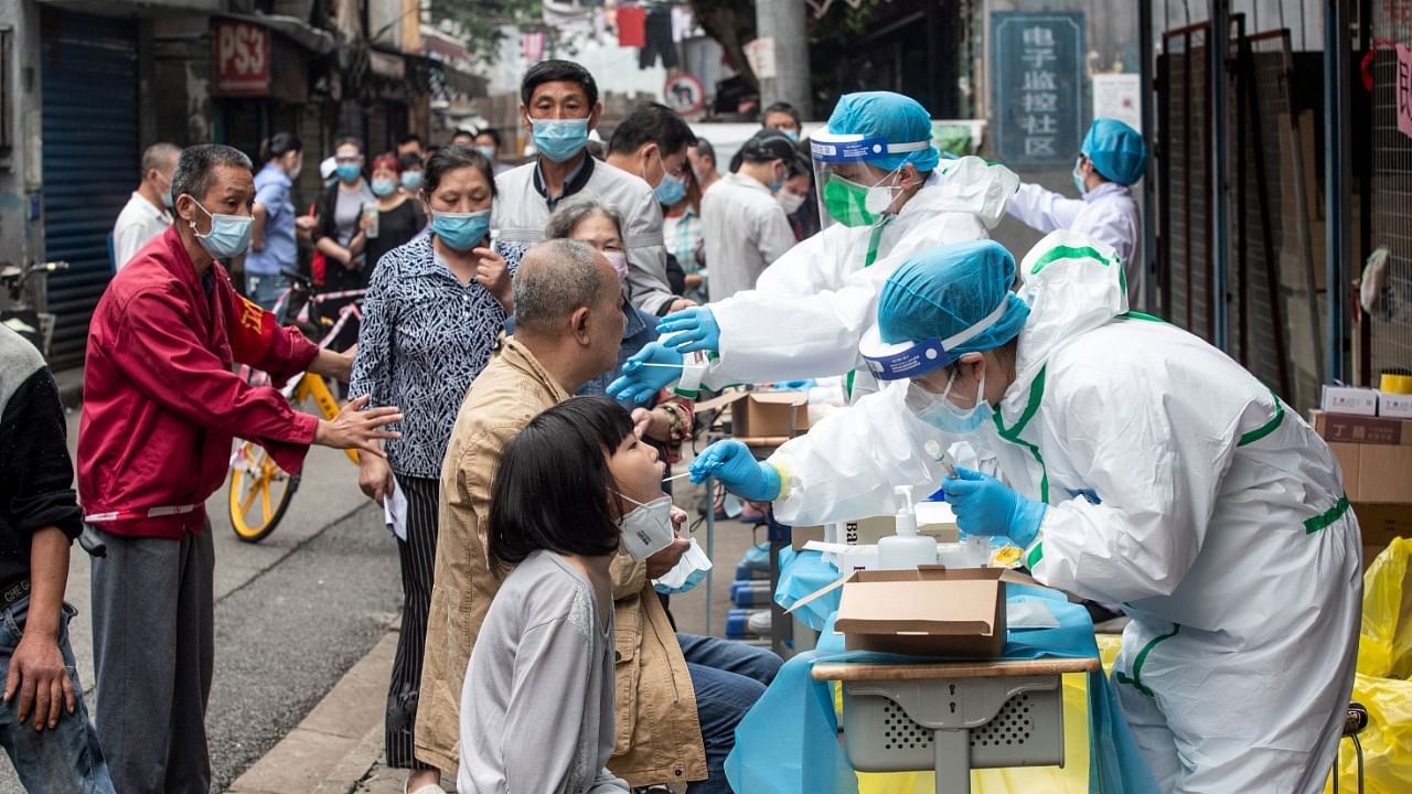 Medical workers take swab samples from residents to be tested for the Covid-19 coronavirus, in a street in Wuhan in China's central Hubei province. Credit: AFP file photo