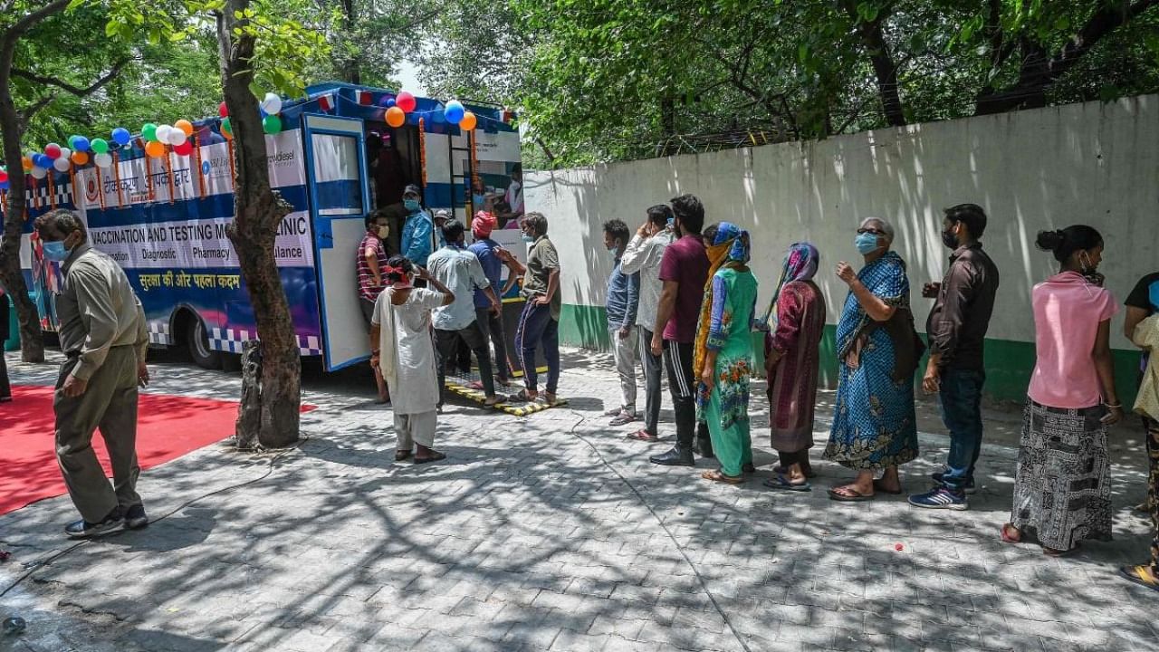 People queue up to get themselves inoculated with the Covid-19 coronavirus vaccine outside a mobile vaccination van in New Delhi. Credit: AFP Photo