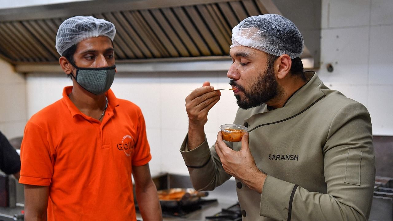 In this photograph taken on June 21, 2021, chef Saransh Goila tastes a dish for a delivery order in the kitchen of the Goila Butter Chicken restaurant in Mumbai. Credit: AFP Photo