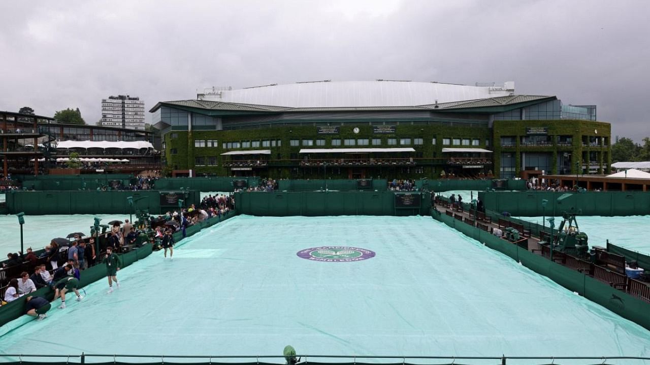 Covers are pictured on the outside courts as rain delays the start of play on the first day of the 2021 Wimbledon Championships at the The All England Tennis Club in Wimbledon. Credit: AFP Photo