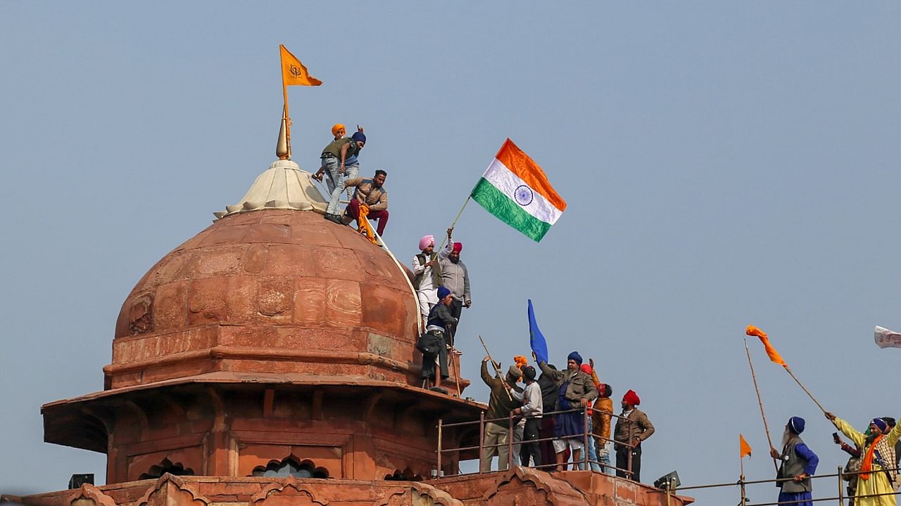 Farmers hoist flags at the Red Fort during the 'tractor rally'. Credit: PTI File Photo