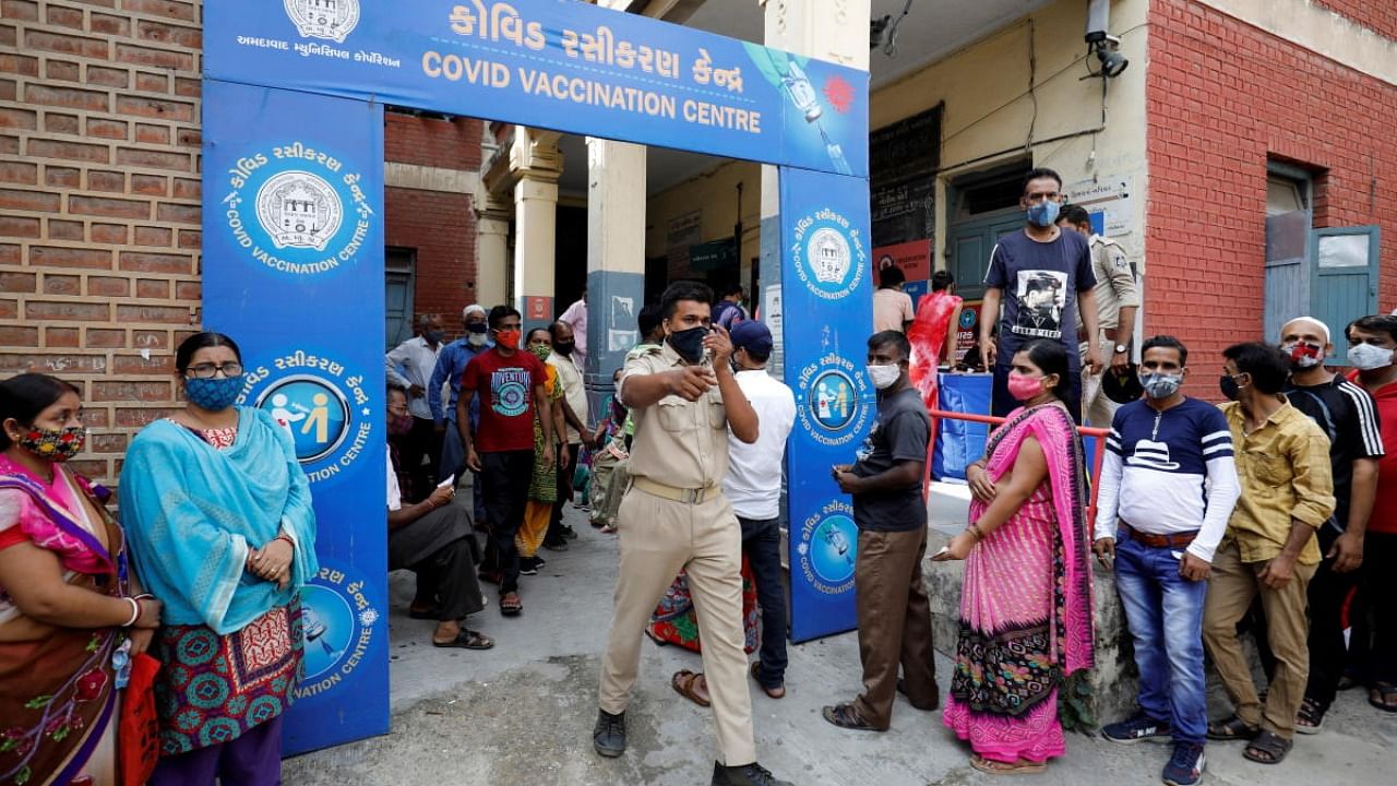 A police officer manages people who came to receive a dose of a coronavirus disease (COVID-19) vaccine outside a vaccination centre in Ahmedabad. Credit: Reuters Photo