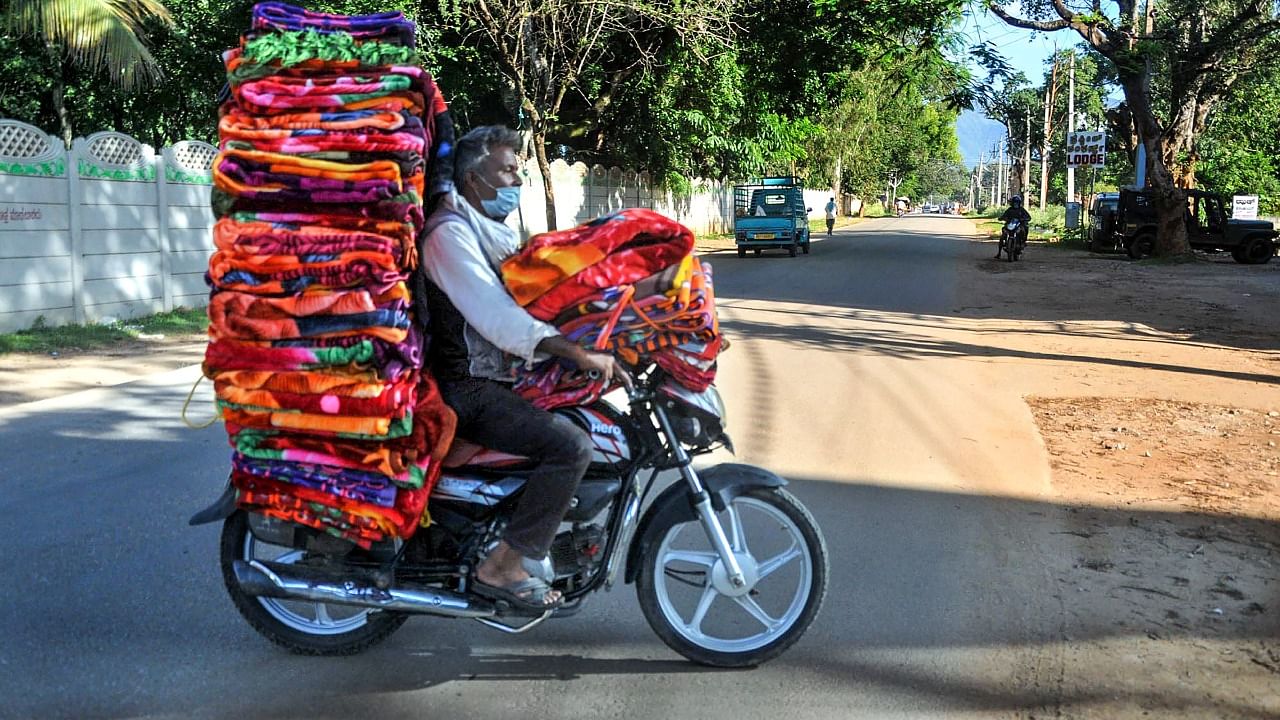 A vendor carries blankets on his motorcycle for sale after further ease in Covid-induced lockdown restrictions, in Chikmagalur, Tuesday, June 29, 2021. Credit: PTI File Photo