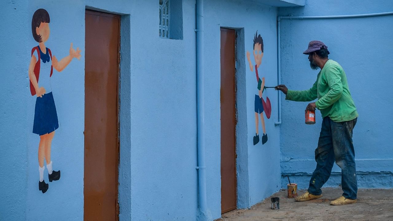 An artist paints indications in front of rest rooms for school children inside the premises of a government primary school premises in Bengaluru on June 26, 2021. Credit: AFP Photo