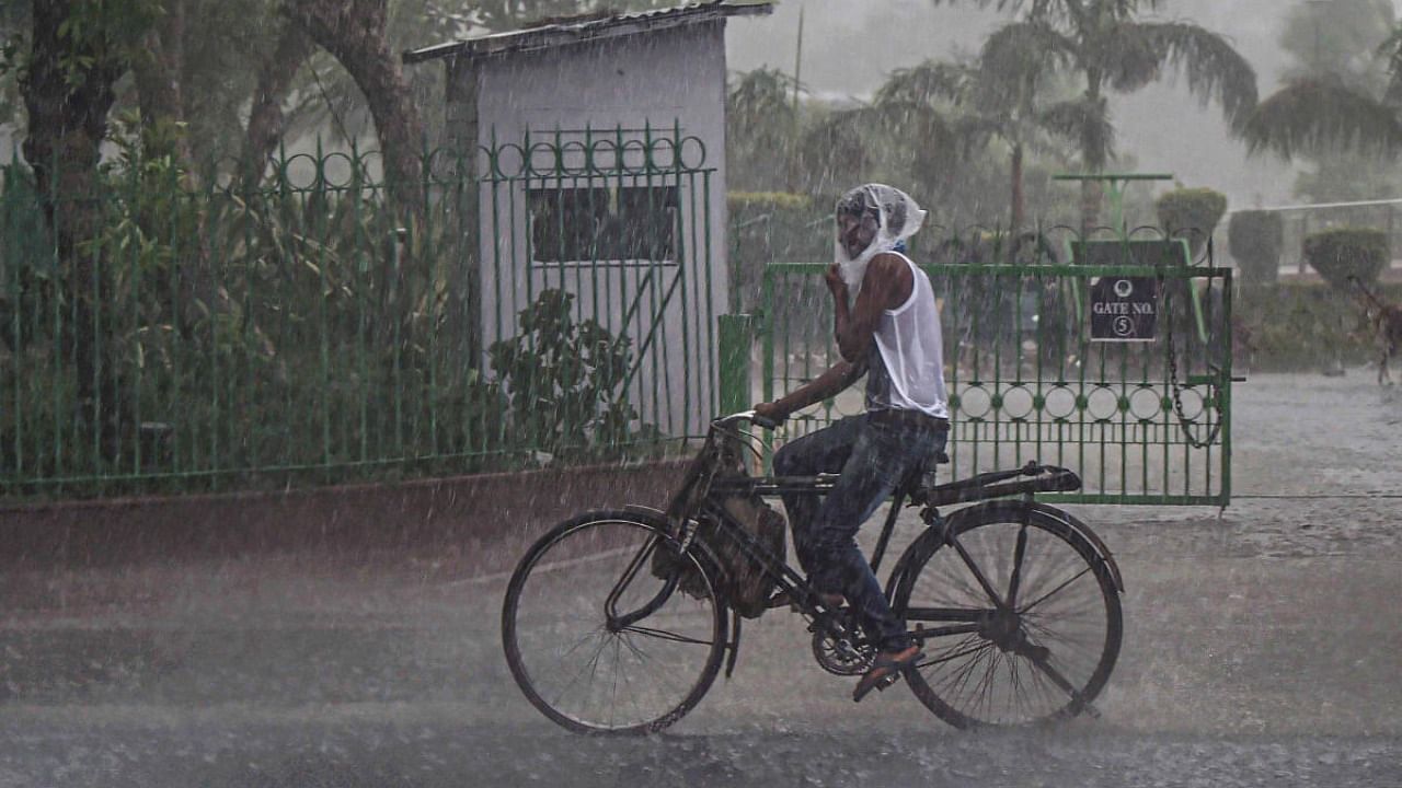A cyclist covers himself with a plastic bubble-wrap sheet during rain, in New Delhi, Saturday. Credit: PTI Photo