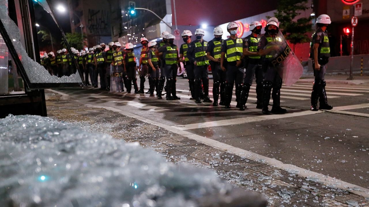 Glass from a smashed bus stop is seen as police form up during a protest against Brazil's President Jair Bolsonaro, in Sao Paulo, Brazil, July 3, 2021. Credit: Reuters Photo