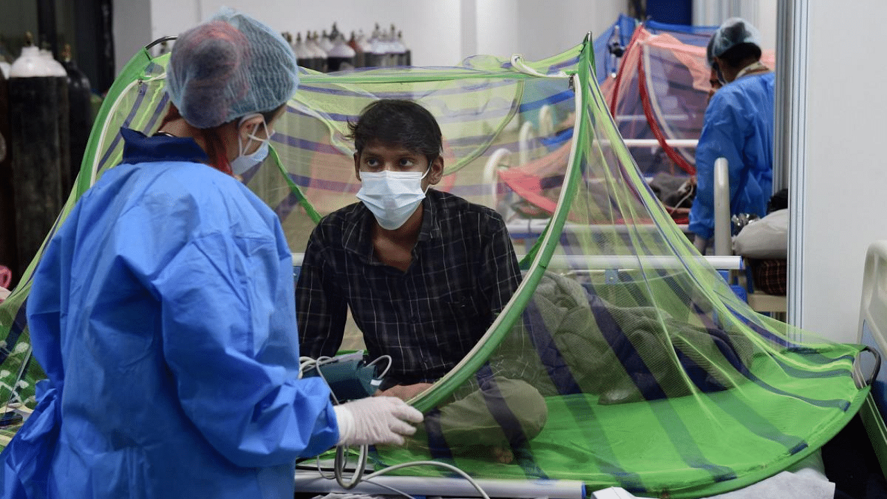 A health worker attends a Covid-19 patient at a Covid care centre at CWG village near Akshardham in New Delhi. Credit: PTI Photo