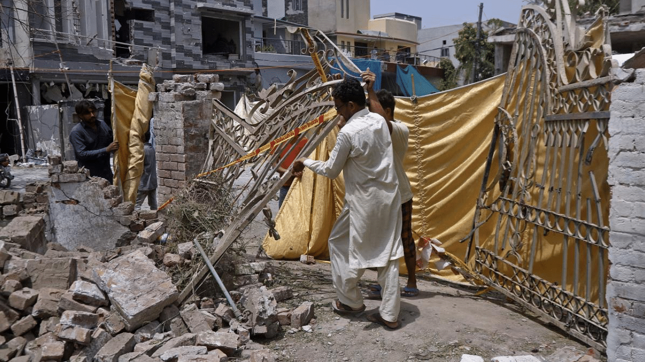  Residents remove a gate from their damaged house at the site of the car bombing. Credit: AP Photo