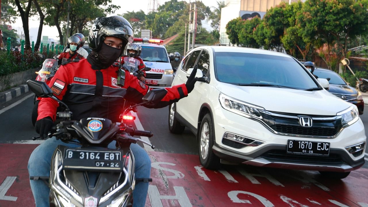 Volunteer bikers escort an ambulance to a cemetery as Covid-19 cases surge in Depok, Indonesia. Credit: Reuters Photo