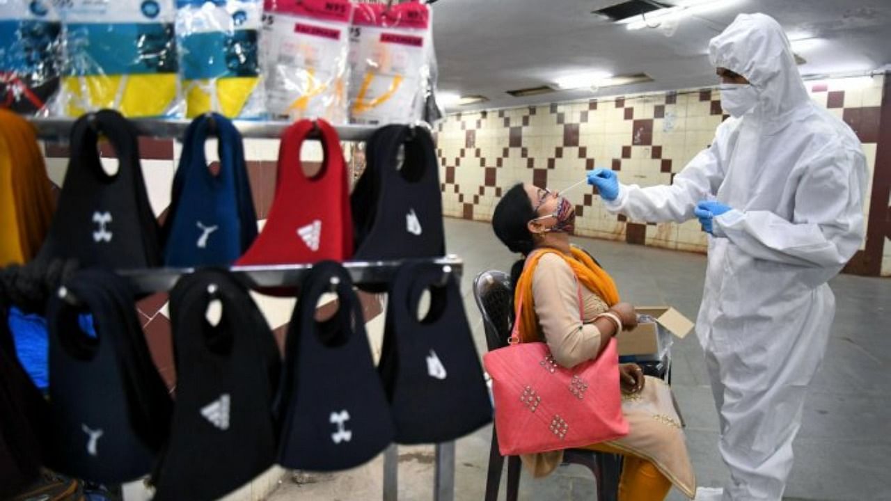 A healthcare worker collects swab sample for coronavirus from people at an underpass between city railway station and Majestic bus stand in Bengaluru on Sunday, July 4, 2021. Credit: DH Photo