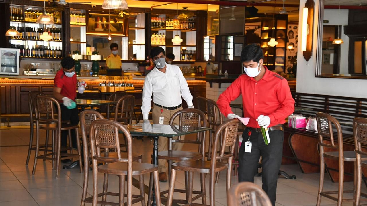 Staff cleans the area at Bob's bar and restaurant as the government announces lockdown relaxations, in JP Nagar, Bengaluru. Credit: DH Photo