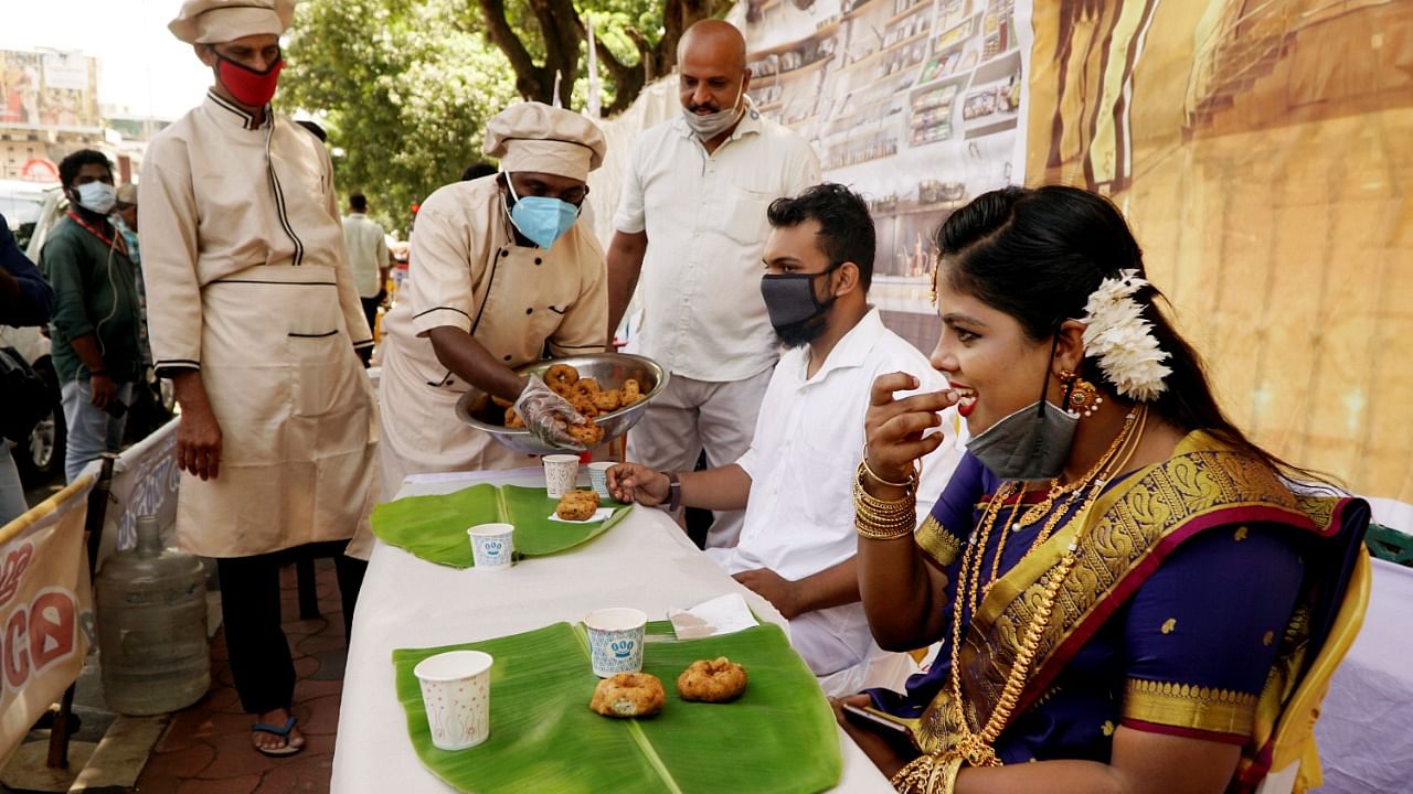 An activist of All Kerala Caterers Association serves a symbolic 'Sadya' in front of the Secretariat, during a protest demanding the state government to permit catering services with adherence to Covid-19 protocols, in Thiruvananthapuram. Credit: PTI photo