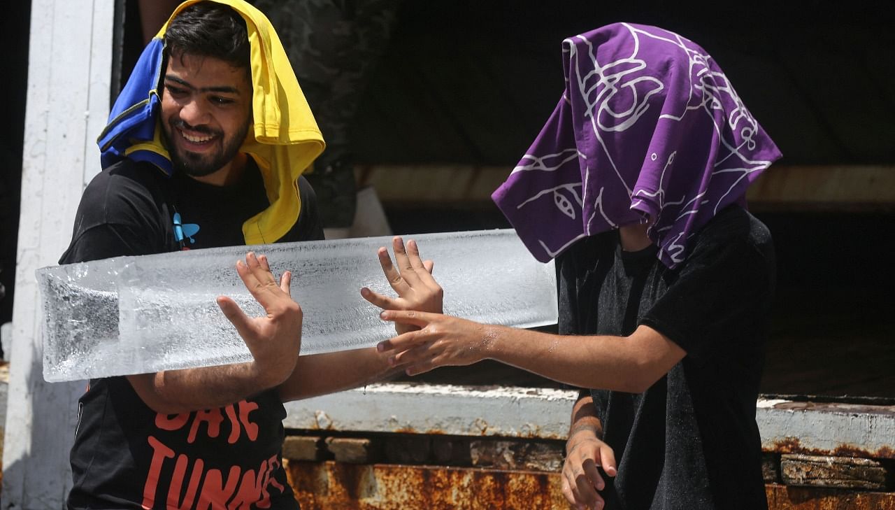 Iraqi youths buy ice blocks at a factory in Sadr City, amid power outages and soaring temperatures. Credit: AFP Photo