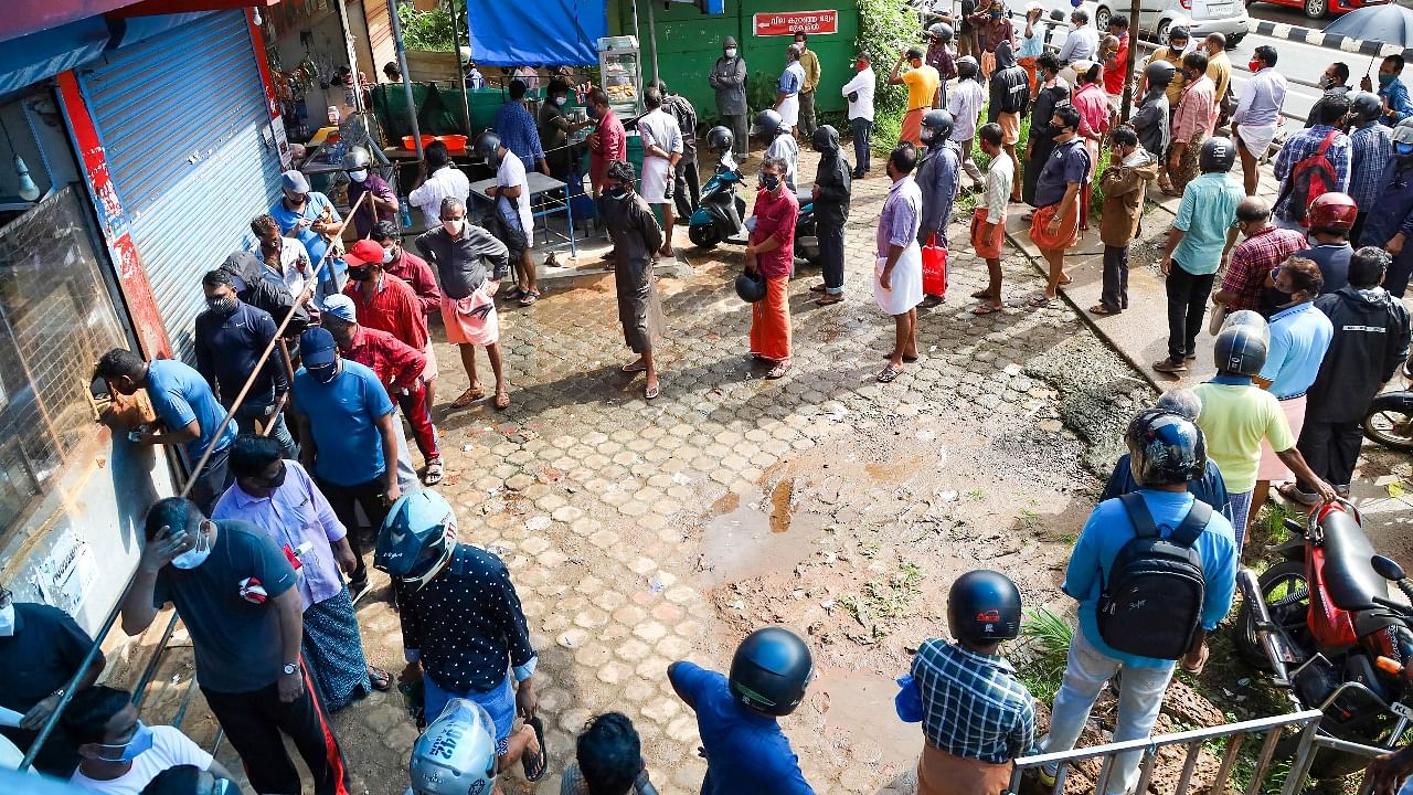 People wait to purchase liquor from a wine shop that reopened after authorities eased some relaxations in the ongoing Covid-19 lockdown, in Kozhikode. Credit: PTI Photo