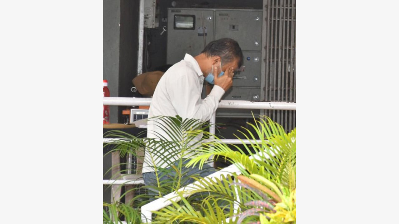 KAS officer Somu Nyamagouda covers his face as he walks into the sub-urban police station in Dharwad on Thursday. Credit: DH Photo