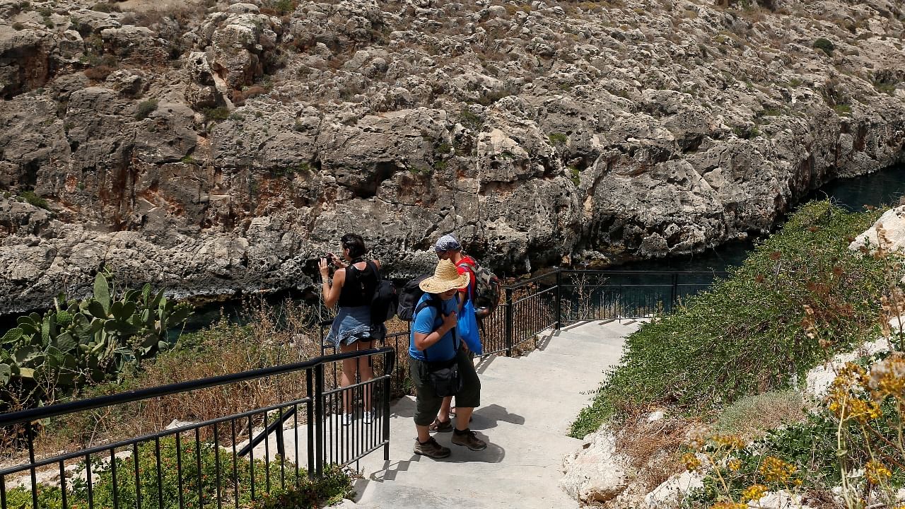 Tourists walk down to the sea in Zurrieq Valley, outside Zurrieq, Malta. Credit: Reuters photo