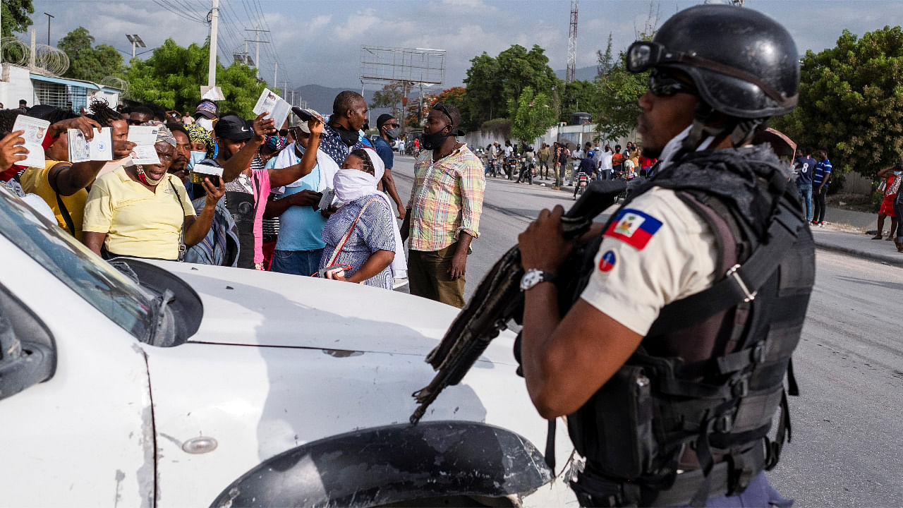 A Haitian National Policeman guard the entrance to the U.S. Embassy as people gather to ask for asylum following the assassination of President Jovenel Moise. Credit: AFP Photo