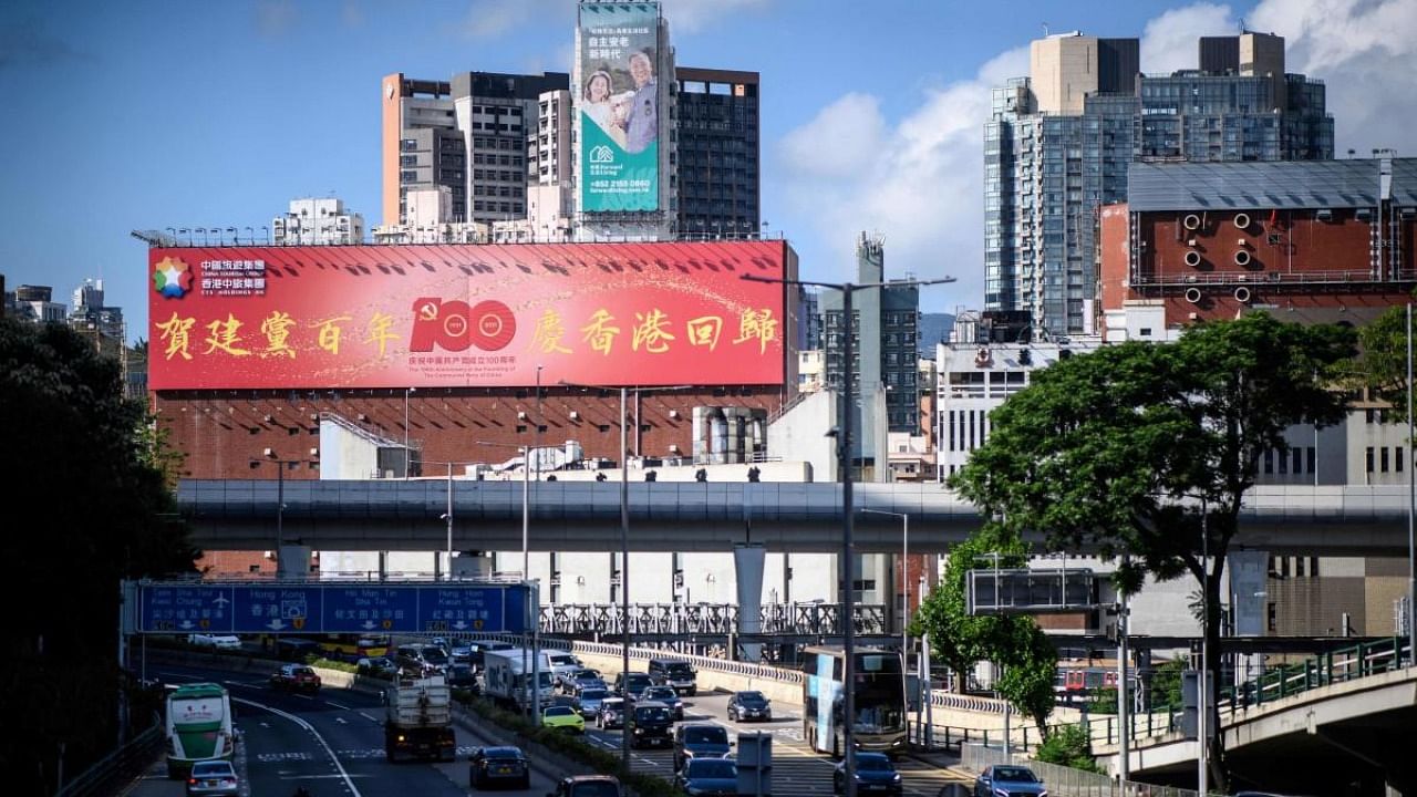 A billboard (L) celebrating the 100th anniversary of the founding of the Communist Party of China is displayed above a main road in Hong Kong. Credit: AFP Photo