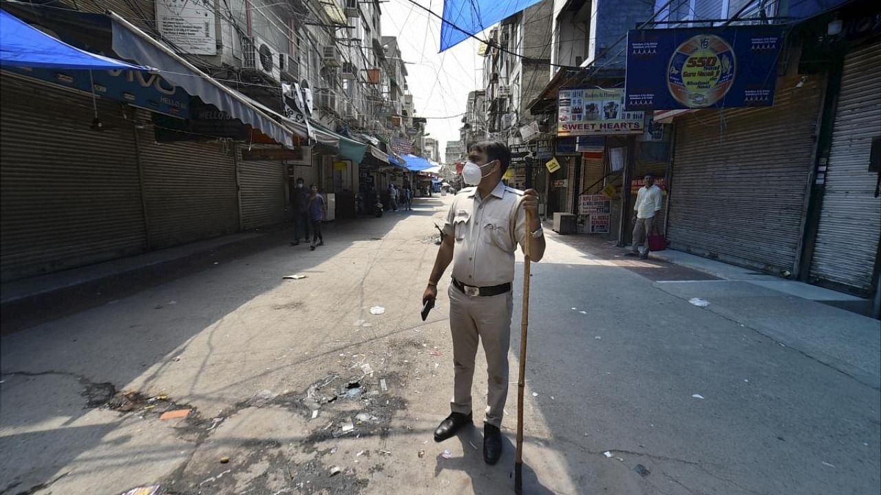 Delhi police personnel stands guard as the Gaffar Market closed for 48 hours for flouting Covid norms in New Delhi. Credit: PTI Photo